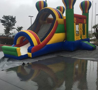 A large inflatable bouncer featuring a colorful slide, perfect for children's outdoor play and entertainment.