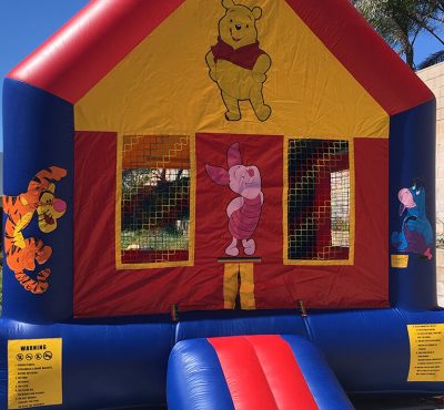 A colorful Winnie the Pooh bounce house featuring Pooh and friends, inviting children to play and jump inside.