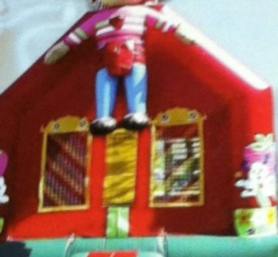 A colorful bouncy castle with a girl joyfully perched on top, smiling and enjoying the playful atmosphere.
