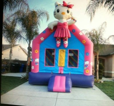 A colorful Hello Kitty bounce house featuring the character's face and playful designs, set up for children's entertainment.